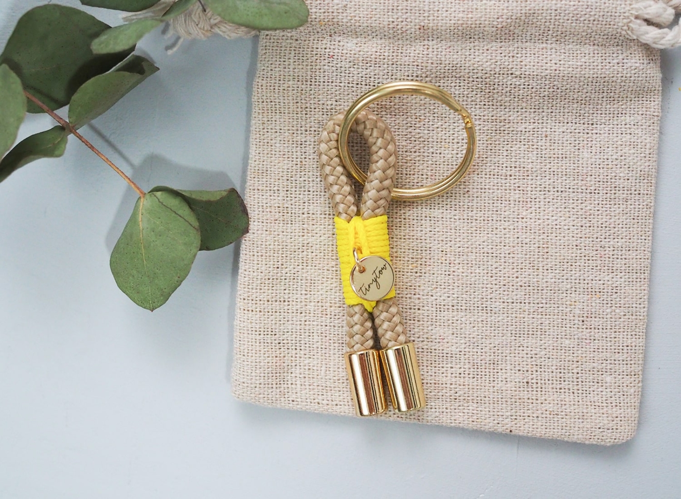 Schlüsselanhänger aus beigefarbenem Tau mit leuchtgelber Takelung, goldenem Schlüsselring.