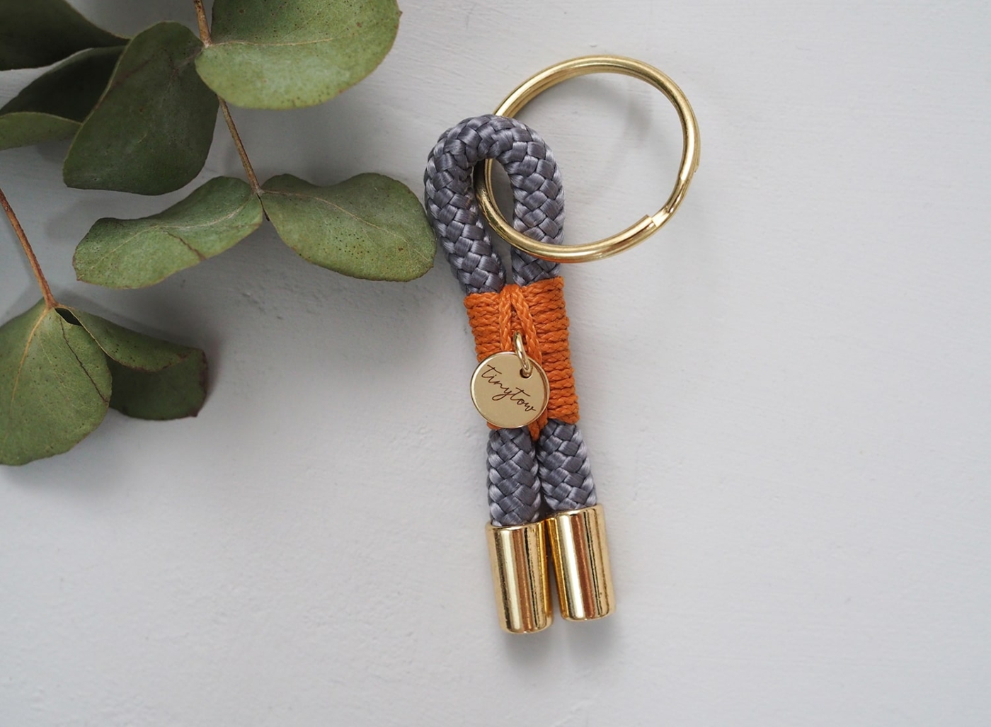 Schlüsselanhänger aus Tauseil in grau mit camelfarbener Umwickelung und goldenen Details.