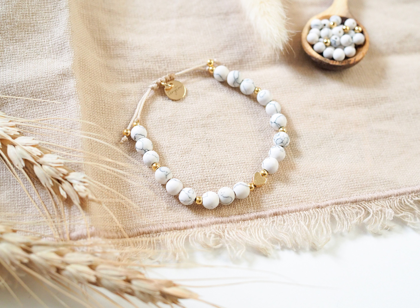 Handgemachtes Armband aus marmorierten, matten Natursteinperlen und goldenen Perlen mit 14K Gold, beigefarbenen Makrmaee-Garn und verstellbarer Schiebeverschluss.