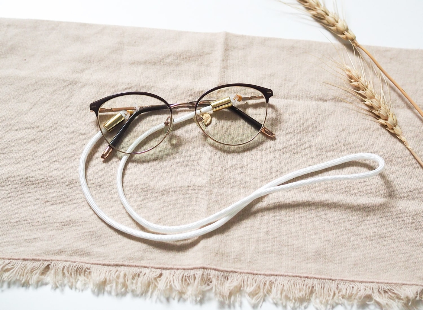 Brillenband aus Nylon/Stoff in weiß mit goldenen Elementen an Brille.
