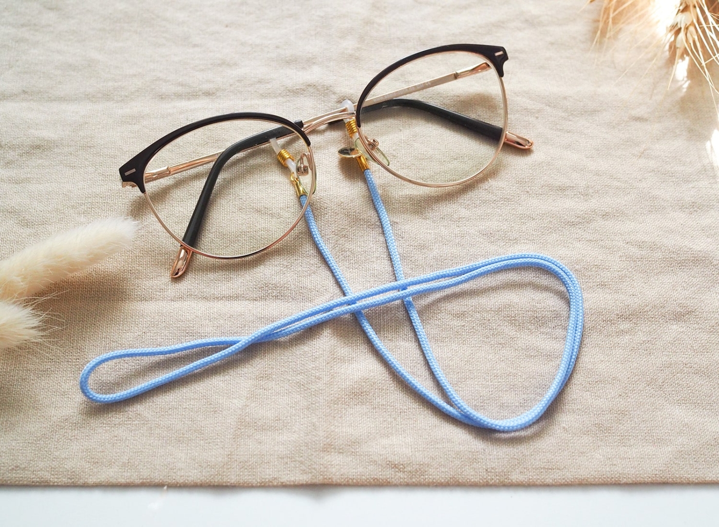Brillenband in hellblau und goldenen Details an Brille.